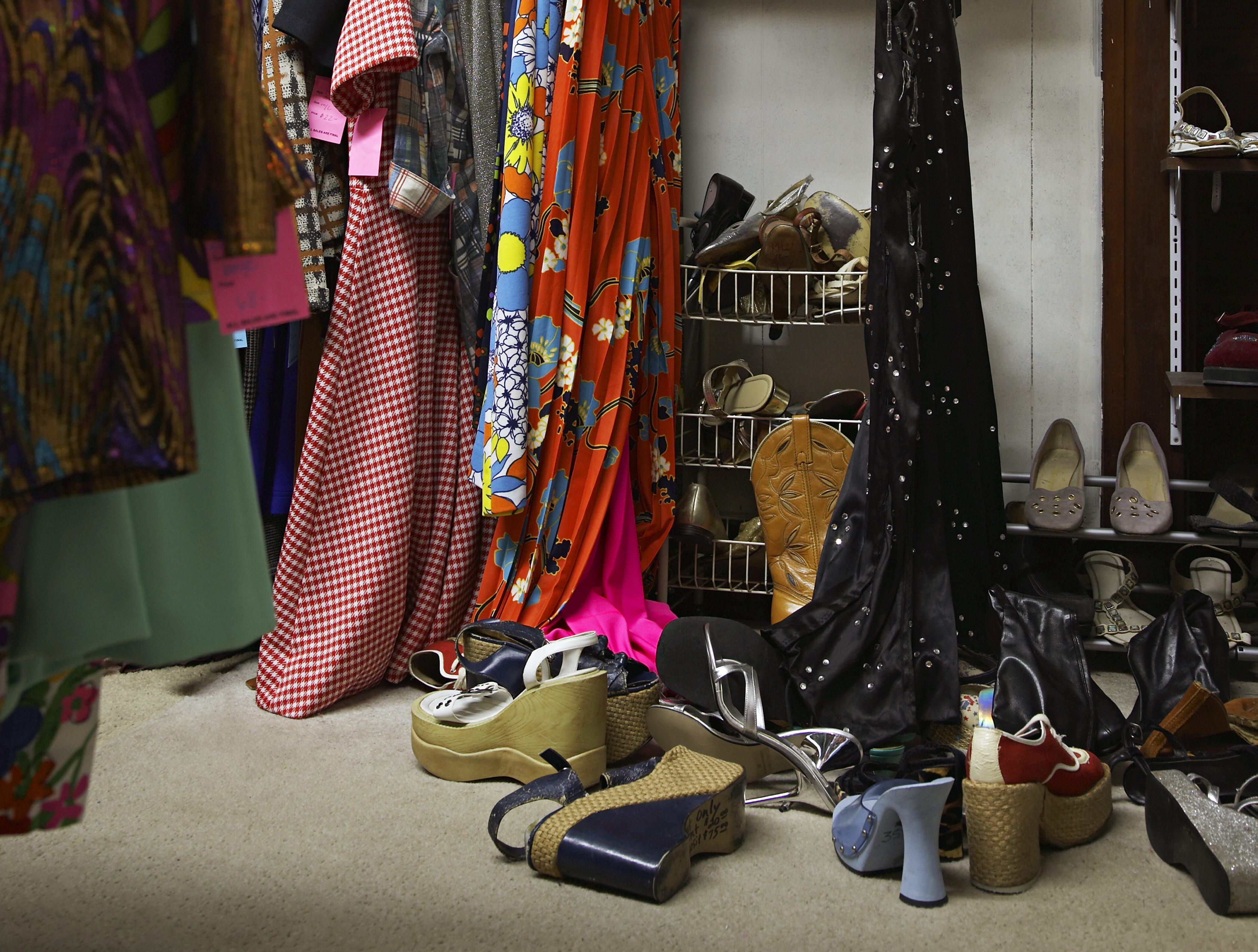 Crowded clothing racks and piled shoes in thrift store