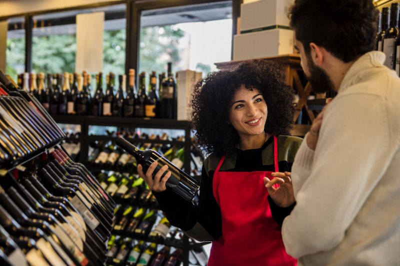 Clerk helping man pick out wine